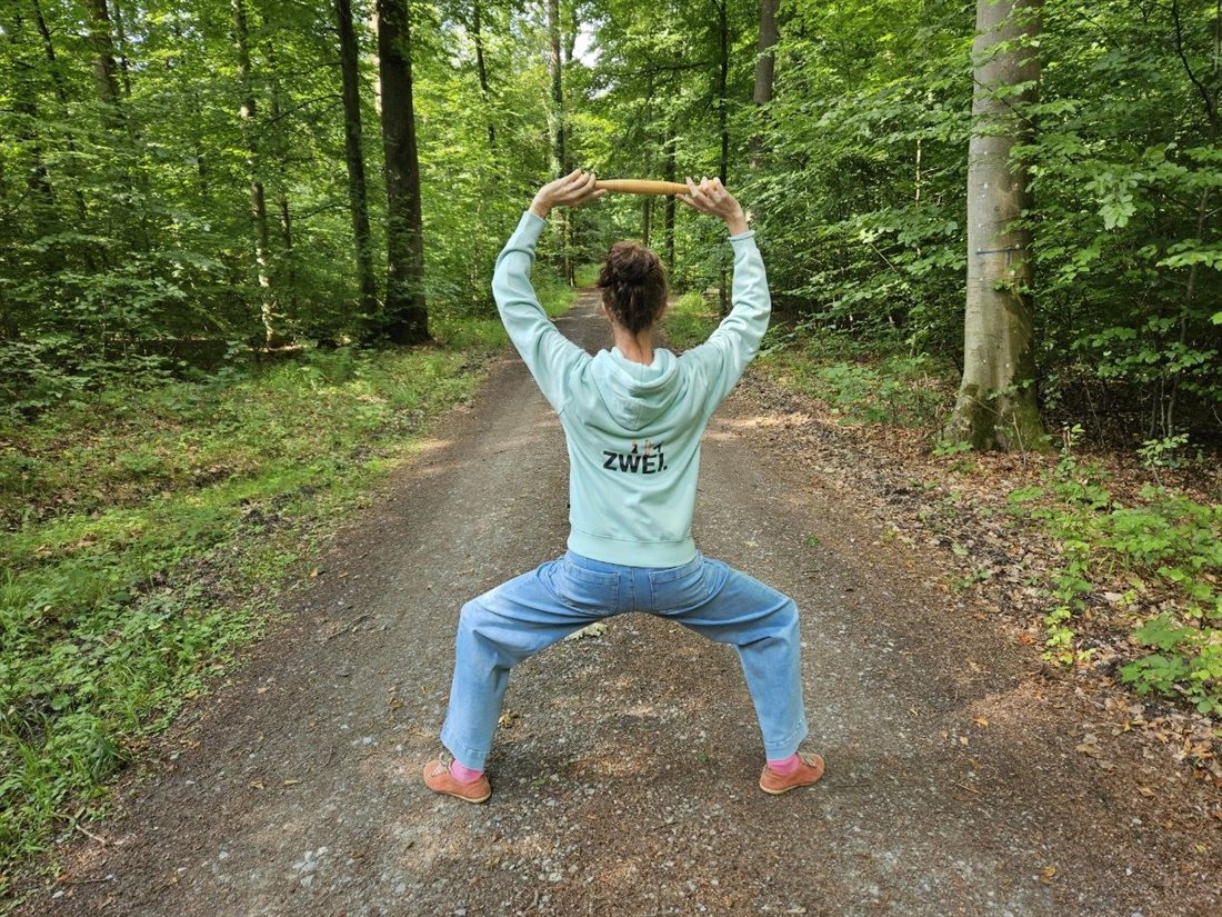 Sylke übt Idogo Qi Gong mit dem Holzstab auf einem Waldweg